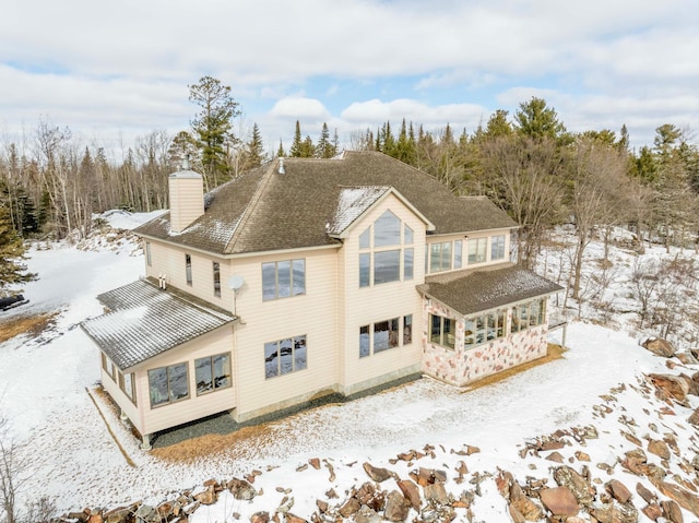 snow covered house with roof with shingles and a chimney