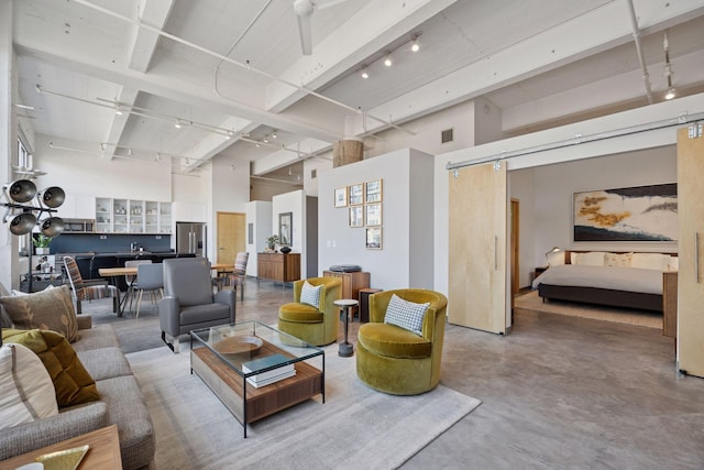 living room featuring finished concrete flooring, a barn door, visible vents, and a high ceiling