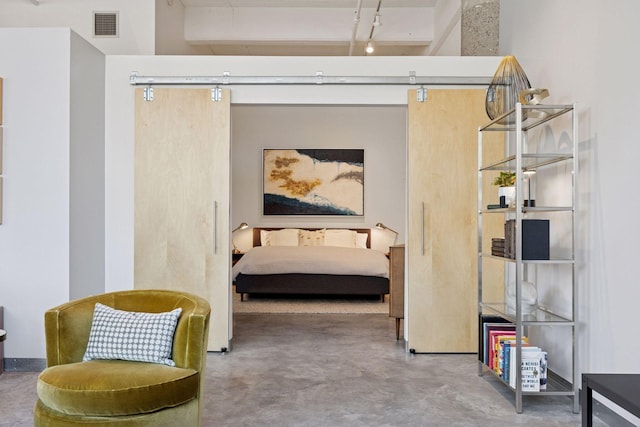 bedroom featuring visible vents, concrete floors, and a barn door