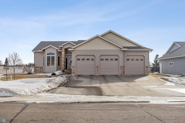 ranch-style home with an attached garage, stone siding, driveway, and fence