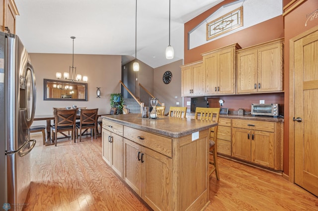 kitchen featuring dark countertops, a breakfast bar, light wood-type flooring, and stainless steel fridge with ice dispenser