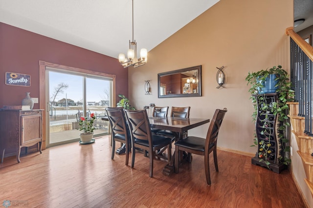 dining space with baseboards, lofted ceiling, wood finished floors, an inviting chandelier, and stairs