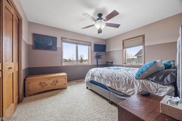 carpeted bedroom featuring a ceiling fan and a textured ceiling