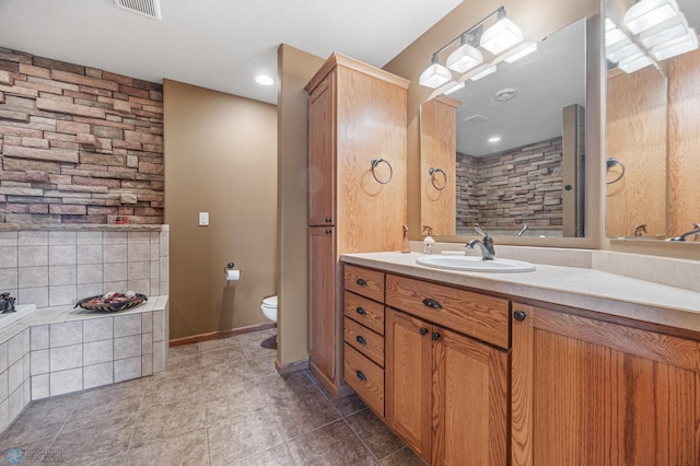 full bathroom featuring tiled bath, visible vents, toilet, vanity, and tile patterned flooring