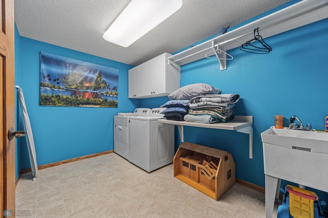 laundry room featuring a textured ceiling, separate washer and dryer, cabinet space, and baseboards