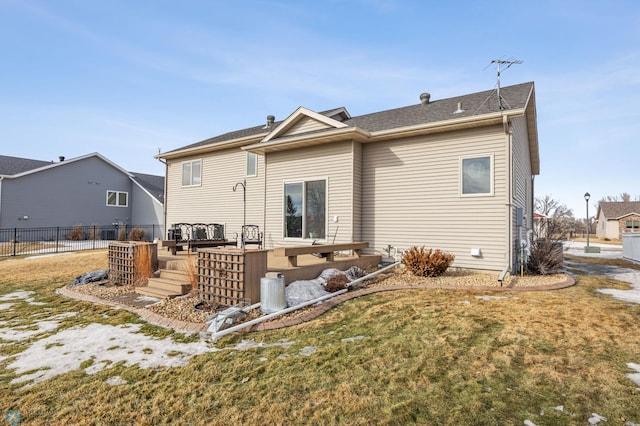 back of house with a lawn, a wooden deck, and fence