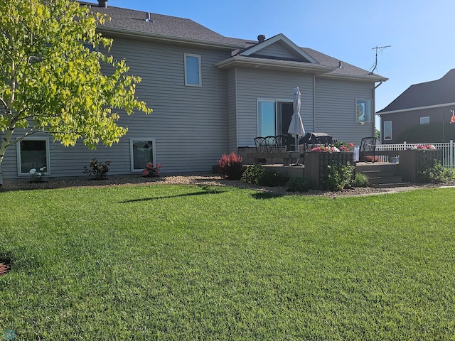 rear view of house with a deck and a yard