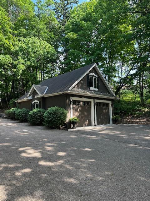 6155 Murray Ct, Shorewood, MN 55331 - view of side of home with a garage, asphalt driveway, and view of scattered trees
