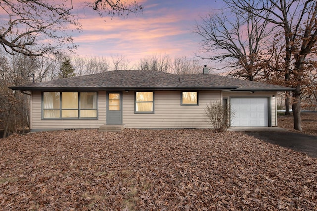 view of front of house featuring a garage, driveway, and roof with shingles