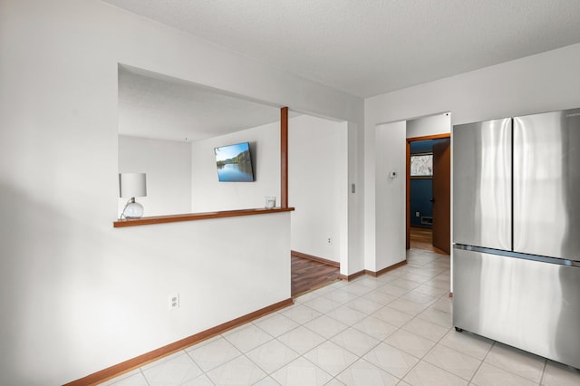 spare room with a textured ceiling, baseboards, and light tile patterned floors