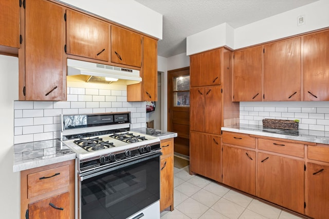 kitchen with under cabinet range hood, white range with gas cooktop, light countertops, and a textured ceiling