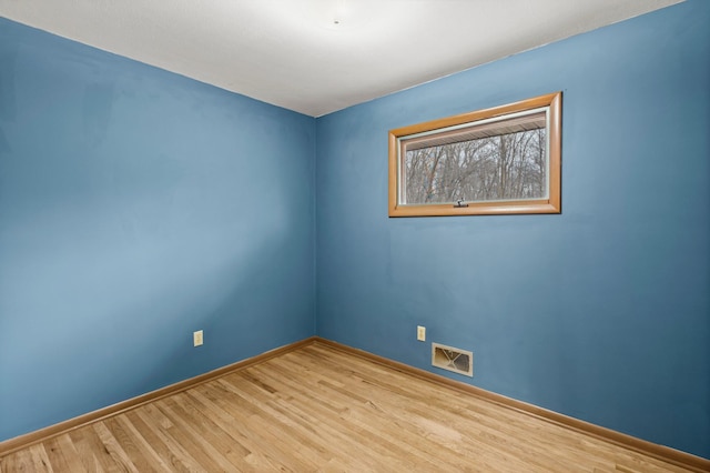 unfurnished room with wood finished floors, visible vents, and baseboards