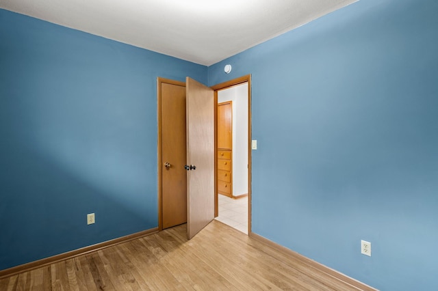 spare room featuring baseboards and wood finished floors