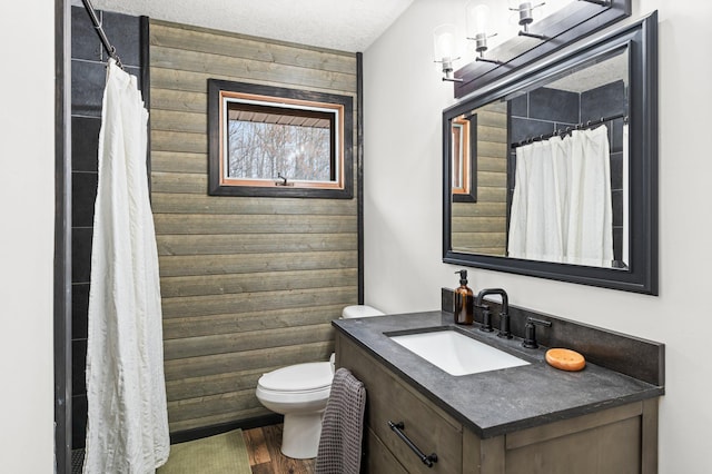 bathroom with vanity, wood finished floors, toilet, and wooden walls