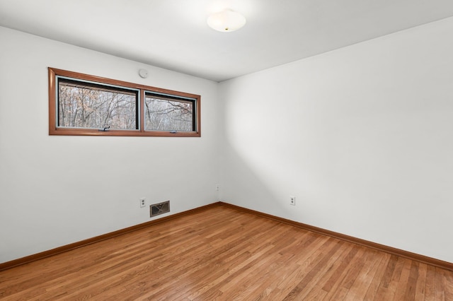 empty room featuring light wood-style flooring, visible vents, and baseboards