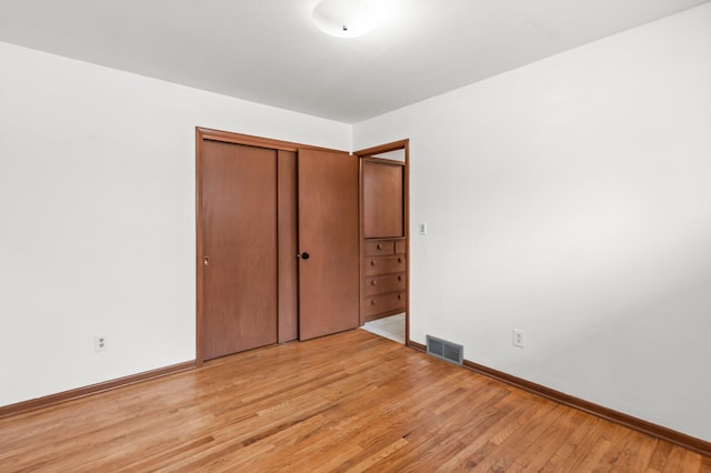 unfurnished bedroom featuring a closet, light wood-type flooring, visible vents, and baseboards