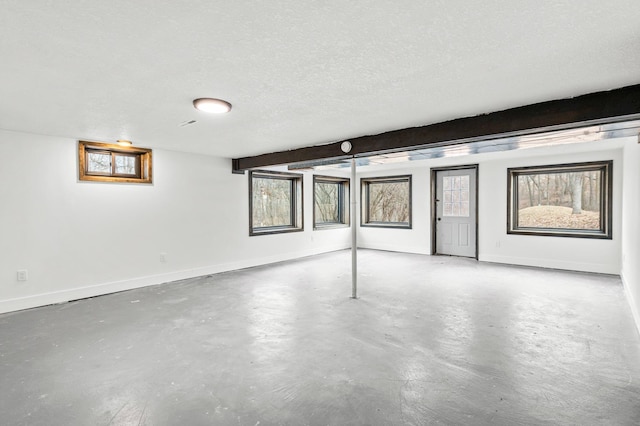 below grade area featuring a textured ceiling, a wealth of natural light, and baseboards