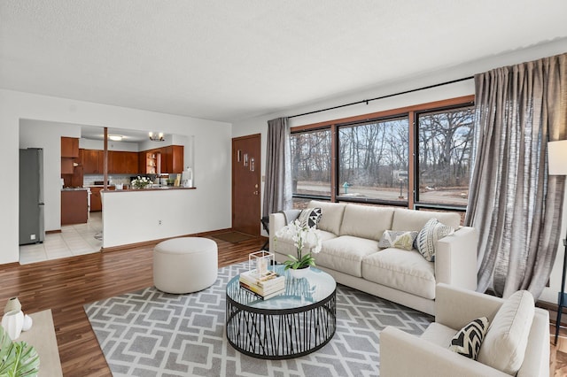 living area with baseboards, a textured ceiling, and light wood-style floors