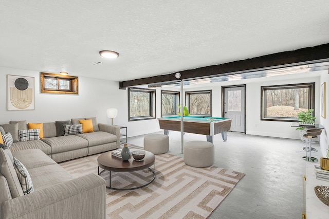 living room featuring a wealth of natural light, a textured ceiling, billiards, and finished concrete flooring
