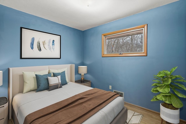 bedroom featuring wood finished floors, visible vents, and baseboards