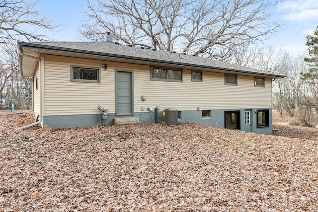 rear view of property with central air condition unit, roof with shingles, a chimney, and entry steps