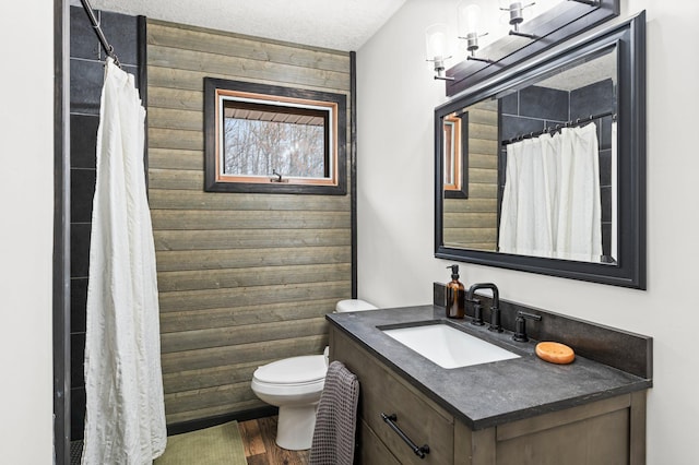 bathroom featuring vanity, a shower with shower curtain, wooden walls, wood finished floors, and toilet