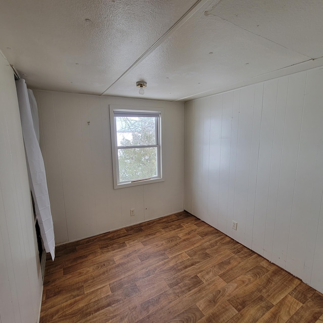 43404 Bills Beach Rd, Edna Twp, MN 56528 - empty room with wood finished floors, wooden walls, and a textured ceiling