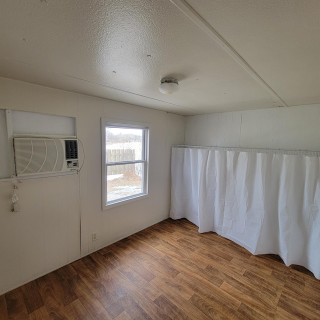 43404 Bills Beach Rd, Edna Twp, MN 56528 - empty room featuring wood finished floors, a wall unit AC, and a textured ceiling