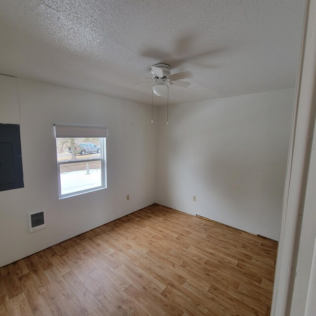 43404 Bills Beach Rd, Edna Twp, MN 56528 - spare room with electric panel, light wood finished floors, ceiling fan, a textured ceiling, and heating unit