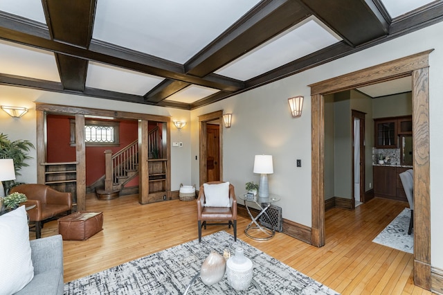 living area featuring stairs, hardwood / wood-style floors, beamed ceiling, and baseboards