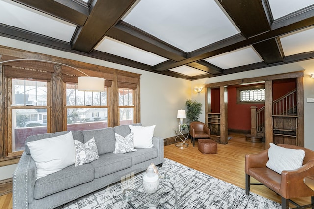 living area featuring baseboards, coffered ceiling, wood finished floors, stairs, and beam ceiling