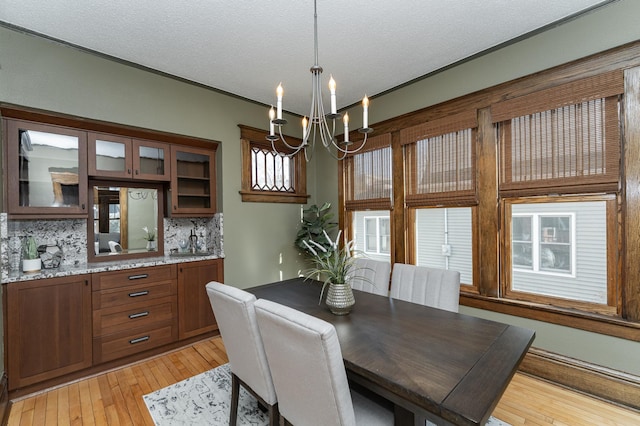 dining space featuring light wood-type flooring, an inviting chandelier, ornamental molding, and a textured ceiling