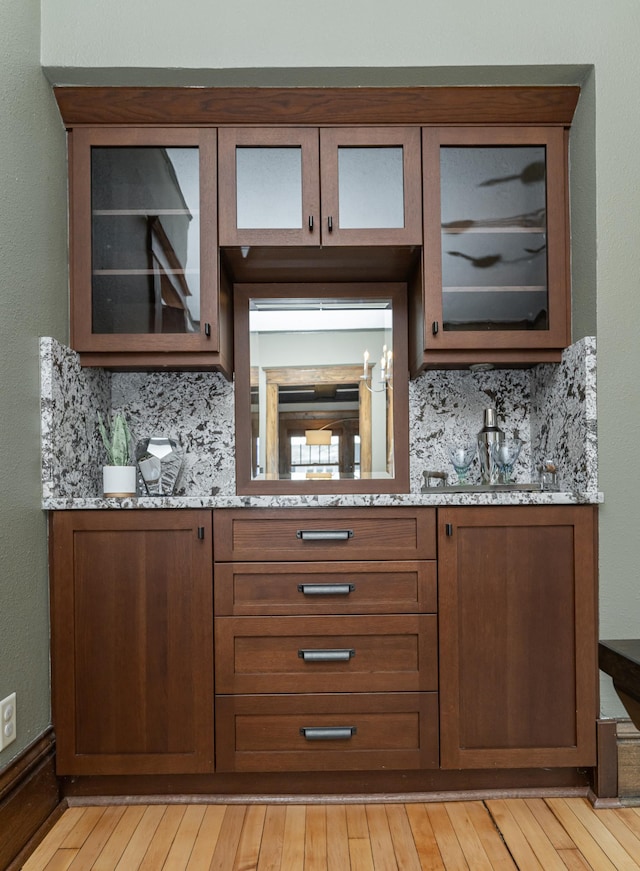 bar featuring light wood-style floors and decorative backsplash