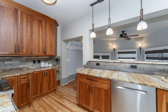 kitchen featuring light stone counters, dishwasher, tasteful backsplash, brown cabinetry, and decorative light fixtures