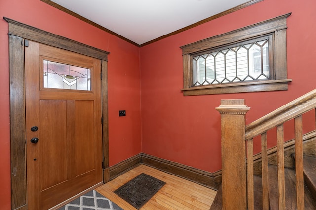 entryway with hardwood / wood-style flooring, stairway, baseboards, and crown molding