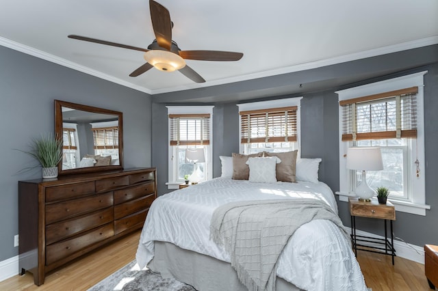 bedroom featuring a ceiling fan, light wood-style flooring, baseboards, and crown molding