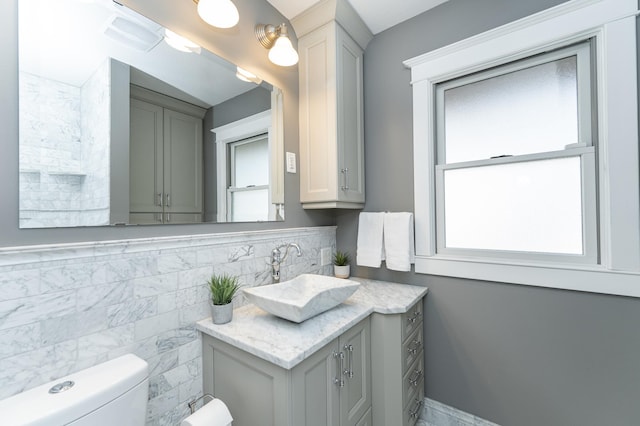 half bath with vanity, toilet, and tile walls