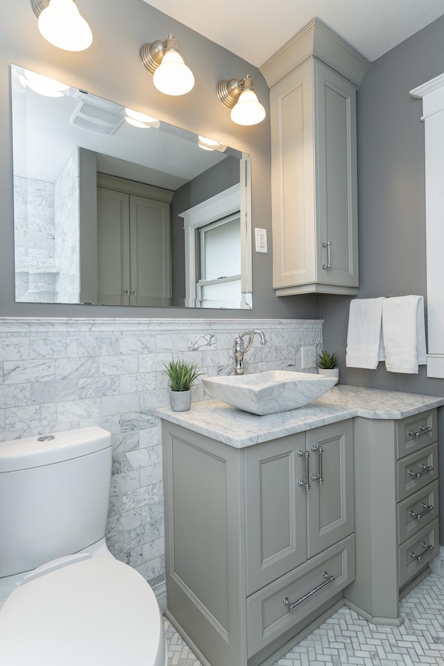 half bathroom with toilet, tile walls, and vanity