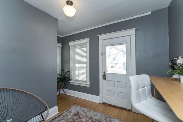 foyer featuring crown molding, baseboards, and wood finished floors