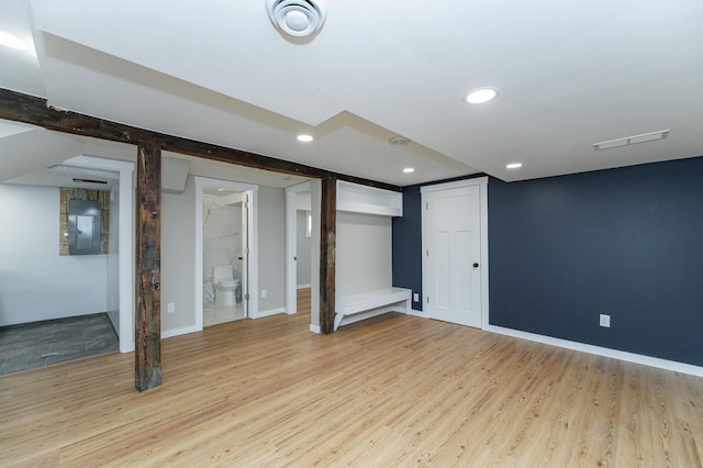 finished below grade area with light wood finished floors, electric panel, visible vents, baseboards, and recessed lighting