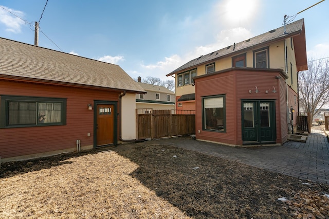 rear view of house with a patio area, fence, and roof with shingles