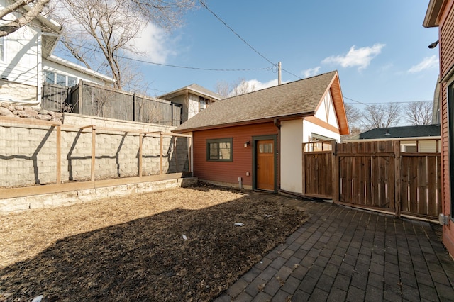 view of home's exterior with a fenced backyard and a shingled roof