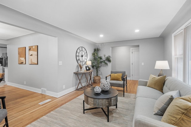 living room with light wood finished floors, recessed lighting, visible vents, and baseboards