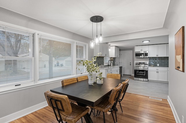 dining space featuring light wood finished floors, visible vents, and baseboards