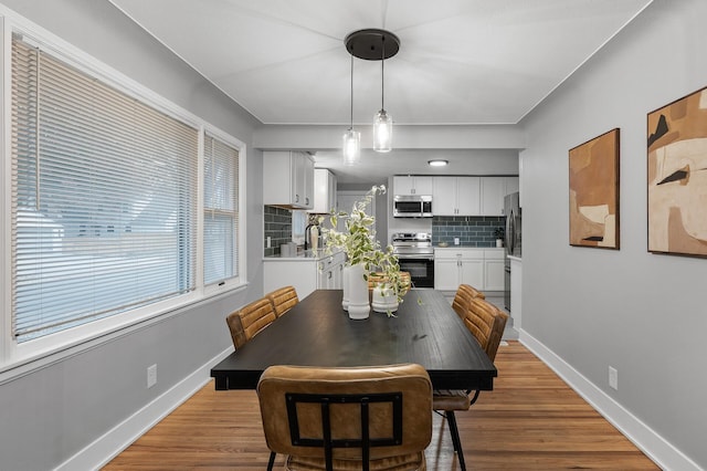 dining room featuring light wood-style flooring and baseboards