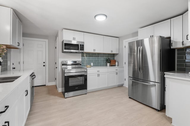 kitchen featuring white cabinets, light wood-style floors, stainless steel appliances, and a sink