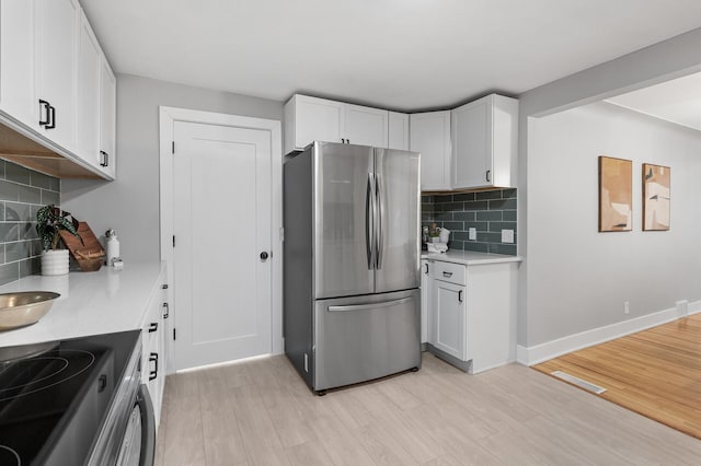 kitchen featuring baseboards, appliances with stainless steel finishes, light countertops, light wood-type flooring, and white cabinetry