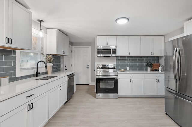 kitchen featuring white cabinets, appliances with stainless steel finishes, light countertops, and a sink