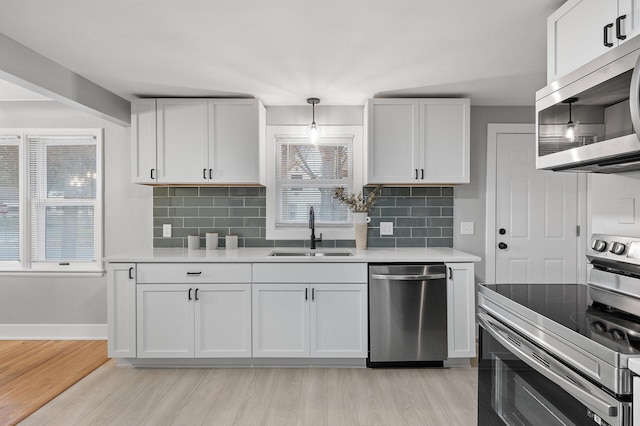 kitchen with stainless steel appliances, a sink, and white cabinets