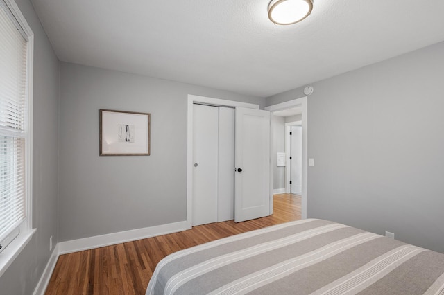 bedroom with a closet, baseboards, and wood finished floors